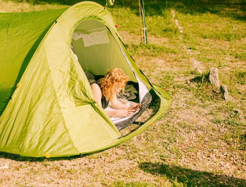 Vrouw in de tent met haar telefoon op het gras